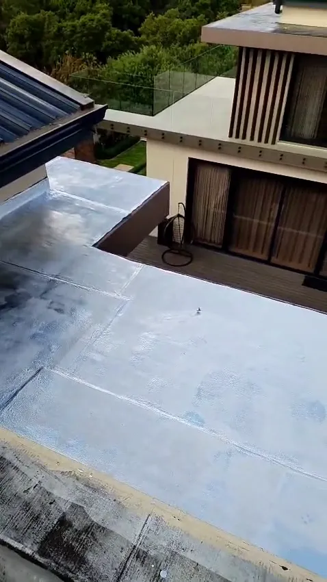 Flat roof and parapet step sealed with torch-on waterproofing, beside a timber deck